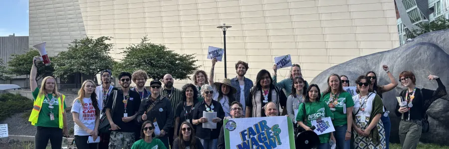 Members of DAMWU stand in front of the Denver Art Museum holding a Fair Wages Now poster.